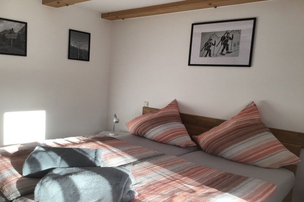 Un dormitori amb un llit, almoines, una tauleta de nit, una làmpada i quadres a la paret.