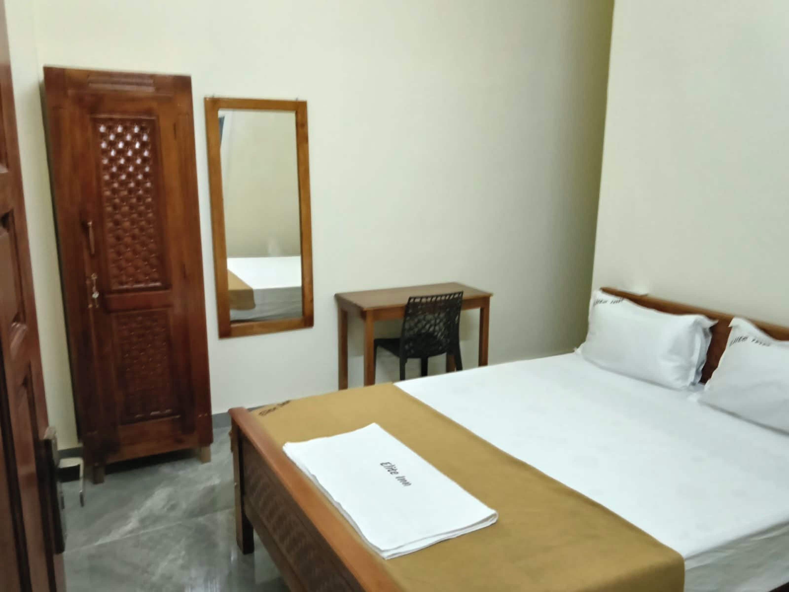 Quarto com cama, escrivaninha de madeira, cadeira, guarda-roupa e espelho.