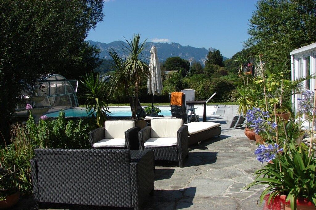 An outdoor seating area with wicker furniture and a pool in the background.