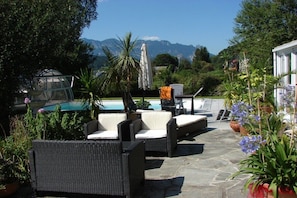 An outdoor seating area with wicker furniture and a pool in the background. - Holiday apartment with 2 bedrooms (Bischofswiesen)