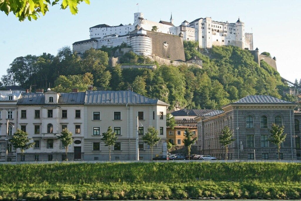 Un château historique perché sur une colline, avec des bâtiments modernes en premier plan.