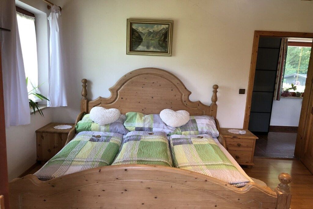 A bed with a wooden headboard, a green and white checkered bedspread, and heart-shaped pillows.