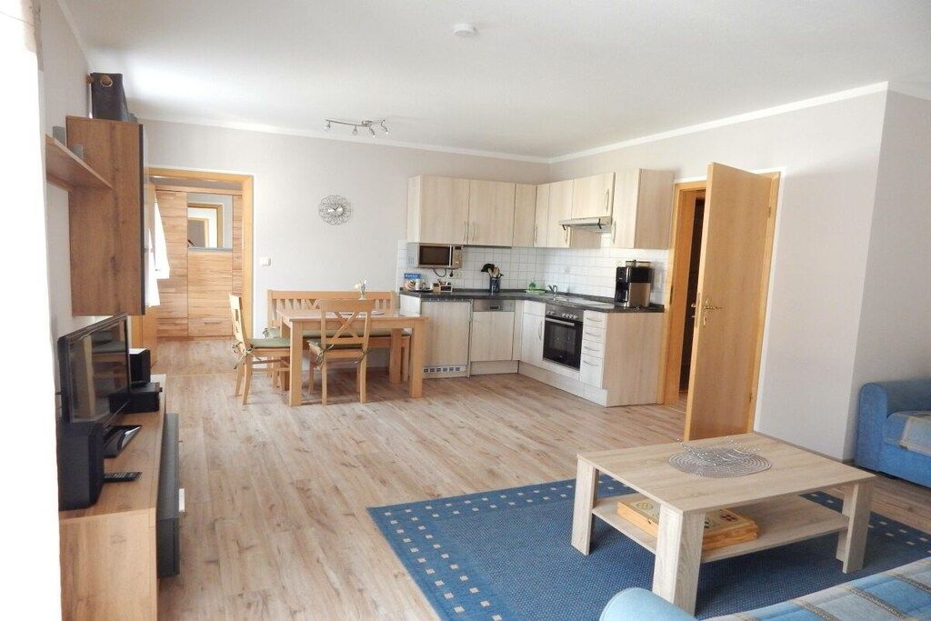 Ett kompakt bostadsutrymme med ett litet kök, en matplats och en sittgrupp.