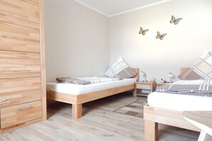 Une chambre avec deux lits, une armoire en bois et un mur décoré d’autocollants représentant des papillons.