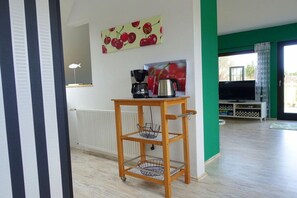 A living room with a wooden coffee table, a radiator, a television, and a green wall. - Holiday apartment with 2 bedrooms (Kappeln-Lüttfeld)