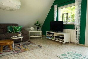 A living room with a sofa, a television, a small table with a plant, and a patterned rug. - Holiday apartment with 2 bedrooms (Kappeln-Lüttfeld)
