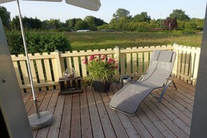 A wooden deck with a lounge chair and a potted plant. - Holiday apartment with 2 bedrooms (Kappeln-Lüttfeld)