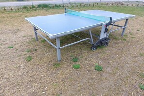 Ein tragbarer Tischtennis-Tisch steht im Freien auf einer grünen Wiese aufgestellt.
