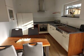 Eine kompakte Küche mit Esstisch, Stühlen, Herd und Fenster.