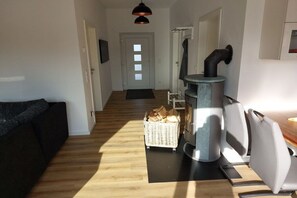 Ein Flur mit einer Couch, einem Kamin, einem Holzkorb und einer Tür.