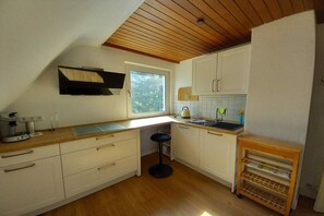 Une cuisine de taille réduite, dotée de meubles en bois, d’un plan de travail, d’un évier et d’une fenêtre qui laisse entrer la lumière naturelle.
