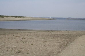 A coastal landscape with a sandy beach and calm water. - Holiday home with 1 bedroom (Bruinisse)