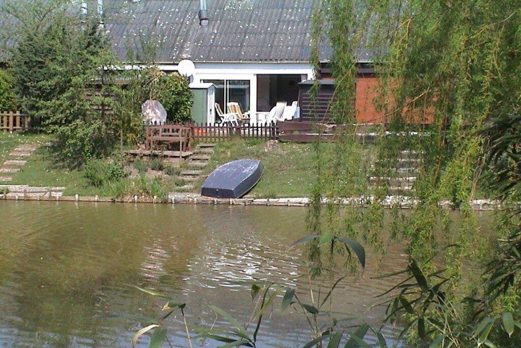 A house with a pond, a wooden deck, and a satellite dish.