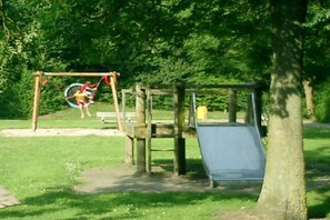 A playground with a swing set and a slide. - Holiday home with 1 bedroom (Bruinisse)
