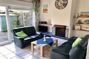 Een woonkamer met een bank, een salontafel, een open haard en een wandklok.