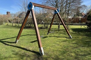 Une balançoire installée dans un espace herbeux, sous un ciel dégagé.
