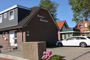 A two-story brick building with a sign reading 'Ferrenhaus Secstein' and a white car parked in front. - Apartment 2 - Seestein Holiday Home (Borkum)