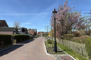 A residential street with houses, a paved walkway, and a wooden fence. - Apartment 2 - Seestein Holiday Home (Borkum)