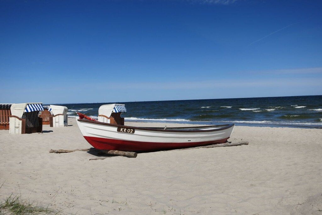 Un bateau portant le numéro d’identification « KROZ » est échoué sur une plage de sable, sous un ciel dégagé.