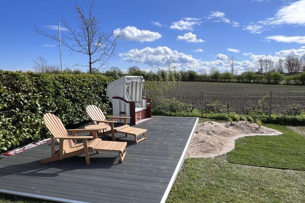 A deck with outdoor furniture, a covered seating area, and a view of a field.