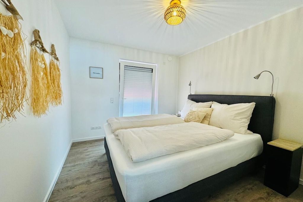 A bedroom with a bed, bedside tables, a lamp, and a window with blinds.