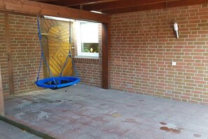 A room with a brick wall, a window with a view, and a blue swing. - Holiday home in Hooksiel with swimming pool (Hooksiel)