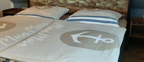 A bed with a headboard featuring a vintage cityscape print, two pillows with a circular design, and a bedspread with a nautical theme.