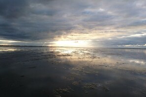 Une plage avec une mer calme et un ciel nuageux.