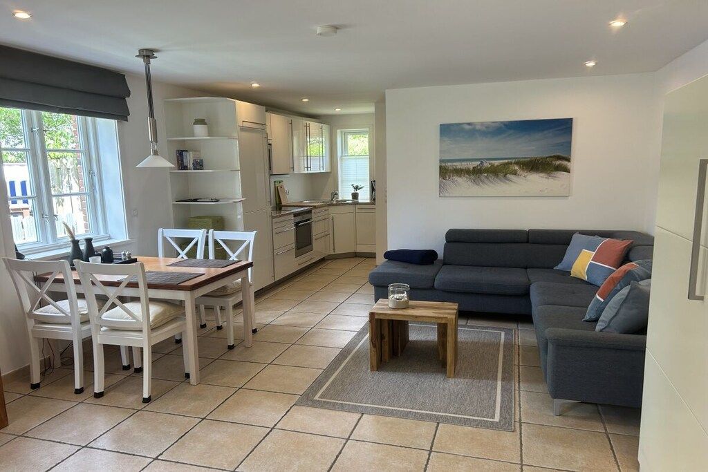 A modern living space with a dining area, kitchen, and a sofa set.