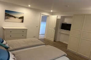Ein Schlafzimmer mit zwei Betten, einem Schminktisch, einem Fernseher und einem Bild an der Wand.