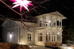 A two-story building with a balcony, large windows, and a snow-covered ground. - Villa Achterkerke / ground floor south & sea (Seebad Heringsdorf)