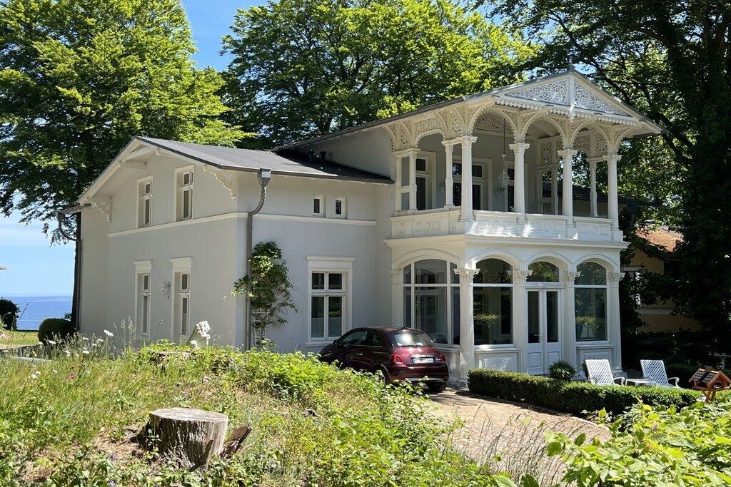 A two-story house with a covered porch and a car parked in front.
