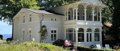 A two-story house with a covered porch and a car parked in front.