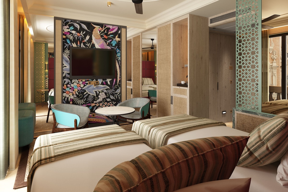 Een hotelkamer met een groot bed, een televisie, een klein rond tafeltje en twee fauteuils.