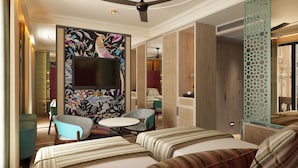 Una habitación de hotel con una cama grande, un televisor, una mesita redonda y dos sillones.