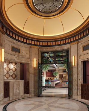 Een statige lobby met een rond plafond, een centrale trap en een zicht op een eetgedeelte.