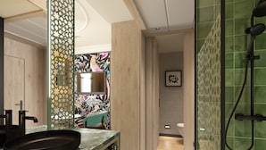 Un baño moderno con un espejo grande, un lavabo negro y una zona de ducha.