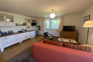 A compact living space with a kitchenette, a sofa, a television, and a lamp. - Holiday apartment with 1 bedroom (Zislow)