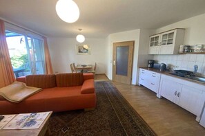 Un espai habitable reduït amb sofà, taula de menjador i petita cuina.