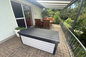 A covered patio area with a table and chairs, a potted plant, and a view of greenery. - Holiday apartment with 1 bedroom (Zislow)