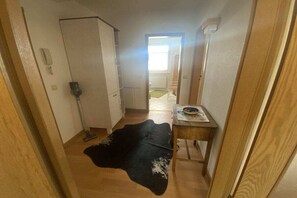 Passadís estret amb un radiador, una catifa negra i una taula de fusta amb un plat i una tassa.