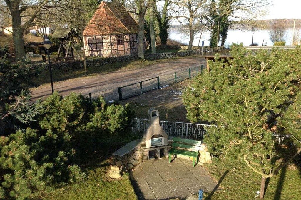 A park with a stone bench, a small building, and a paved path.