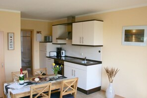A compact kitchen with white cabinets, a microwave, and a sink. - 2 in the house by the water (Ziemitz)