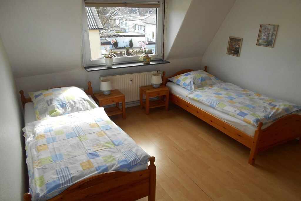 A room with two wooden beds, a window with a view of buildings, and a radiator.