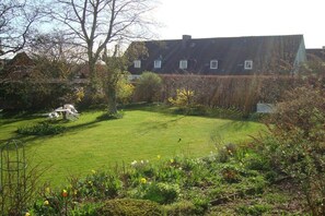 A residential property with a well-maintained lawn, a garden with various plants, and a large house in the background. - Holiday apartment with 2 bedrooms (Flensburg)