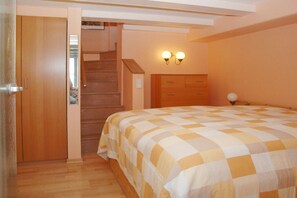 A bedroom with a bed, wooden wardrobe, and a staircase. - Holiday apartment with 1 bedroom (Stexwig)