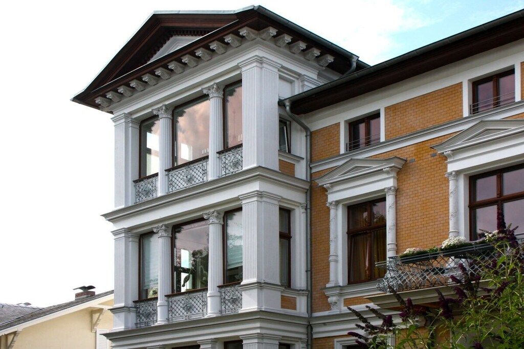 A multi-story building with a corner bay window, white decorative trim, and a brick facade.