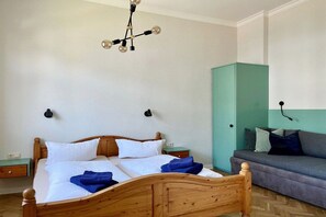 A room with a wooden bed, a teal wardrobe, a grey sofa, and a black pendant light. - Villa Kramme - close to the beach & central (Seebad Heringsdorf)