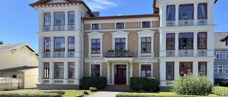 A two-story building with a symmetrical facade, large windows, and a central entrance.