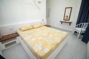 Een slaapkamer met een bed, nachtkastjes, een stoel, een spiegel en een wandplank.